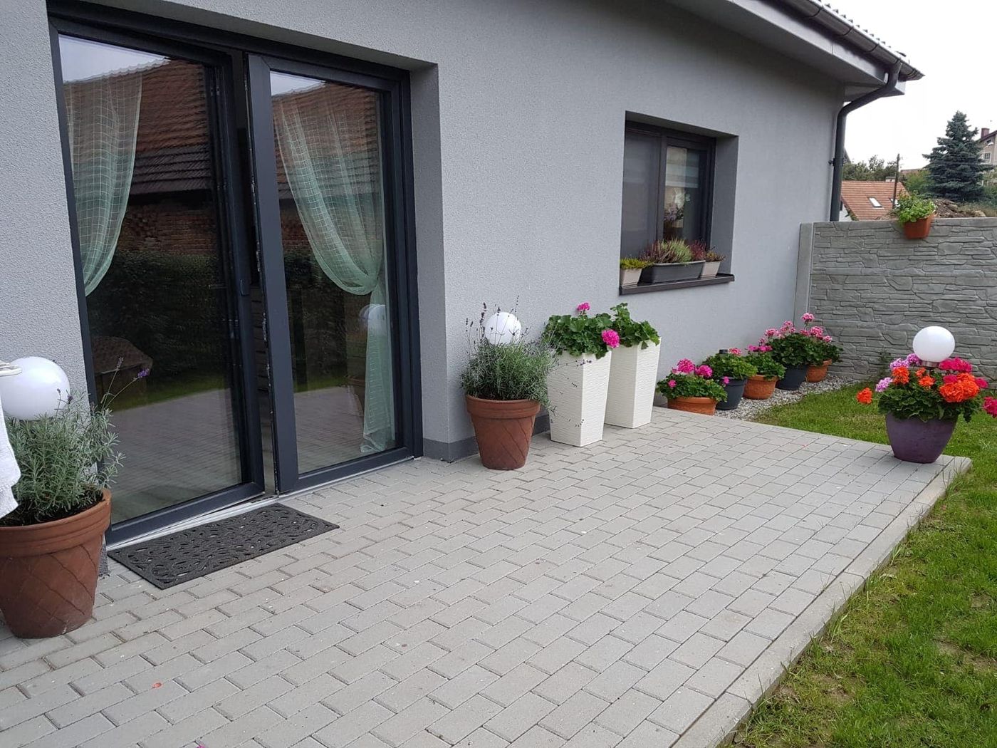 Brukowany taras apartamentu z donicami pełnymi kwiatów