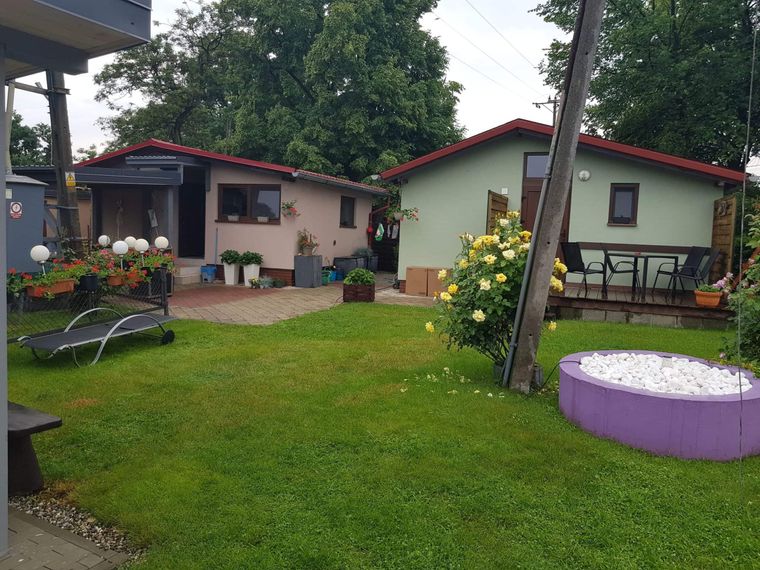 Domki ośrodka Wodnik z tarasami, rabatami kwiatowymi i basenikiem dla dzieci