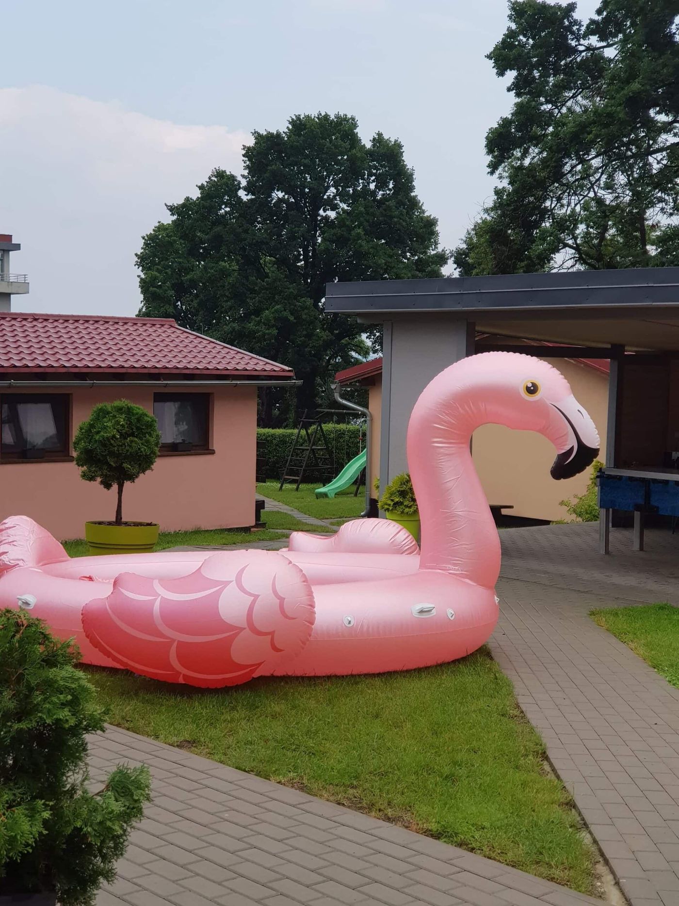 Trawnik przy domkach z dmuchanym flamingiem i zjeżdżalnią dla dzieci