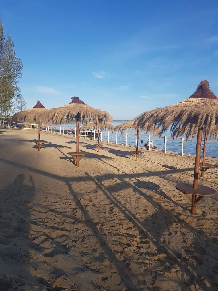 Piaszczysta plaża nad Jeziorem Nyskim z parasolami ze słomy