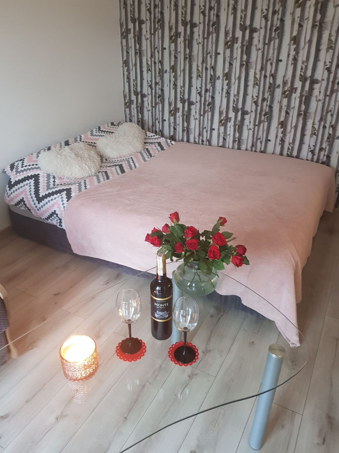Łóżko przygotowane na pobyt romantyczny — róże, wino i kieliszki